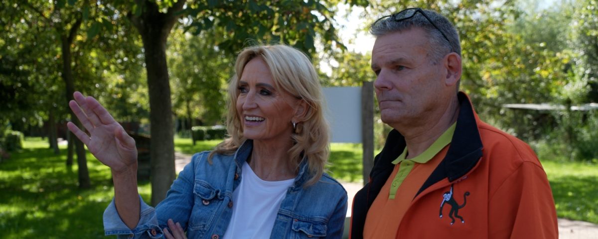 Een man en een vrouw kijken schuin langs de camera terwijl ze met elkaar praten.