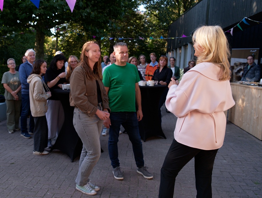 One person is giving a speech while other people stand around to listen to her.